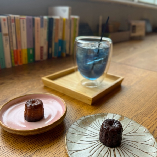 カヌレとジュースと奥に並んだ本